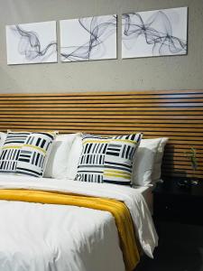 a bedroom with a white bed with four pictures on the wall at Impèrio Boutique Guest Lodge in Siyabuswa +30 photos