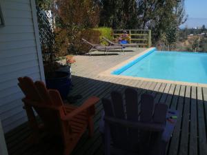 a backyard with a swimming pool and two chairs and a table at Algarrobo cercano a la playa, en lugar tranquilo ,rodeado de naturaleza in Algarrobo