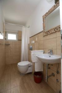 een badkamer met een wastafel, een toilet en een spiegel bij Apartments Jolie in Vodice