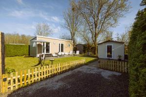 a tiny house in a yard with a fence at De Frije Fûgel - Een luxe chalet op De Friese Wadden in Tzummarum