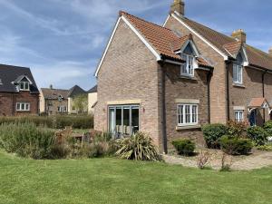 a brick house with a lawn in front of it at Caramel Cottage at The Bay Filey, sleeps 6, 2 dogs welcome for free too in Filey