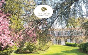 a sign in front of a building with pink flowers at LES 15 CHENES Chambres d hôtes, parc arboré de 5000 m2 à 20KM du PUYDUFOU Une suite familiale et 3 chambres doubles in Saint-Mesmin