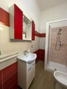 a bathroom with a sink and a shower with red cabinets at Casa Letizia a 2 passi dal centro in Marsala +9 photos
