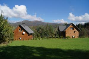 two houses in a field with mountains in the background at Domek Pod Jawornikiem in Wetlina