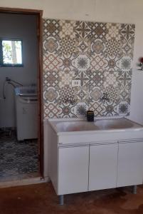 a kitchen with a sink and a tile wall at Chácara aconchegante, próximo Águas de Santa Bárbara in Santa Bárbara do Rio Pardo
