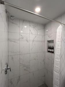 a bathroom with a shower with white marble walls at Hotel La Residence du Voyageur in Montréal