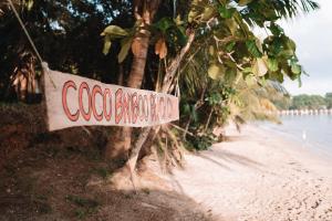 MiramarCoco Bamboo Beach Camp的挂在海滩上树上的标志