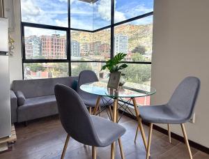 拉巴斯Lujoso Monoambiente en excelente ubicación的有大窗户的房间里有一张桌子和几把椅子