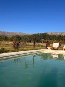 a pool of blue water with a table and a bench at Ranchos de la Tata in Las Calles