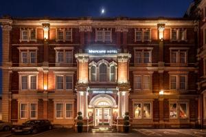 un gran edificio de ladrillo con la puerta delantera iluminada por la noche en Mercure Exeter Rougemont Hotel en Exeter