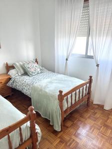 Un dormitorio con dos camas y una ventana. en Casa Paraíso, en Moaña