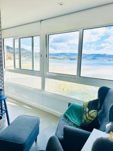 una sala de estar con vistas a la playa desde las ventanas en Casa Paraíso, en Moaña
