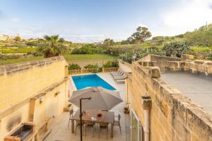a patio with a table and an umbrella and a pool at Surwig Gozitan Villa & Pool - Happy Rentals in Kerċem