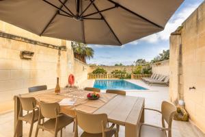 a dining room with a table and chairs and a pool at Surwig Gozitan Villa & Pool - Happy Rentals in Kerċem