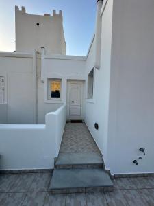 a white house with a white door and stairs at Mare Monte Suites 1 in Parasporos