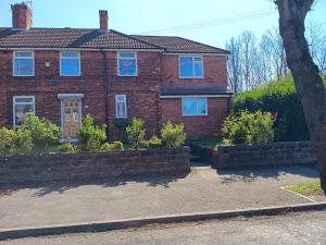 a red brick house with blue windows and bushes at High Street House WEST BROMWICH in West Bromwich