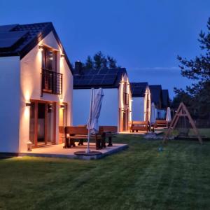 una casa con cortile con panchine e ombrellone di Zagroda ciszy a Lubiatowo