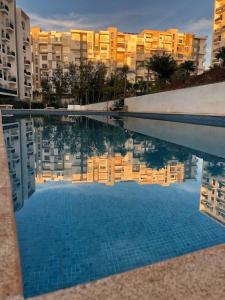 a swimming pool with a reflection of buildings in the water at Boho 2BR Cozy App Jacuzzi & Pool in Rabat