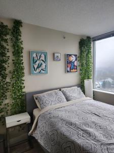 バンクーバーにあるModern High-Rise 1 Bedroom Condo with water view near stadiumsのベッドルーム1室(ベッド1台付)、植物のある窓が備わります。