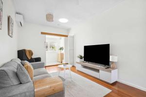 Geelong WestにあるCosy Townhouse in the Heart of Geelong Westのソファと薄型テレビのあるリビングルーム +2枚の写真