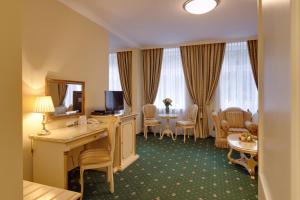a hotel room with a desk and a living room at Hotel Saint Petersburg in Karlovy Vary