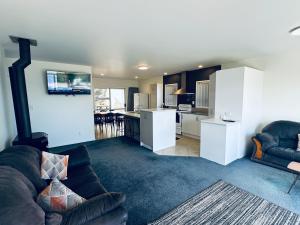 a living room with a couch and a kitchen at Mukies Foreshore 2,0 in Ahipara