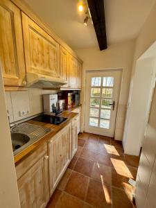 a kitchen with wooden cabinets and a tile floor at Hof Fetthörn, Ferienzimmer Muschel in Giekau