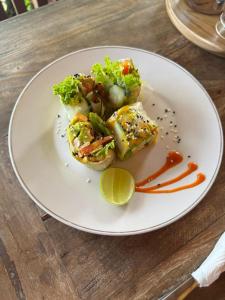 a white plate with food on a wooden table at Puri Sari Villas, Restaurant and Bar in Nusa Lembongan