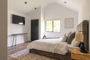 une chambre blanche avec un grand lit et une télévision dans l'établissement Tulum Style in Sherman Oaks, à Garnsey