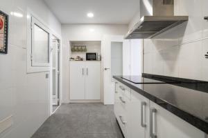 a kitchen with white cabinets and a black counter top at Casa Centro Histórico Almería - Jayrán in Almería
