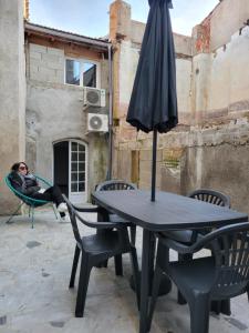 eine Frau, die auf einem Stuhl neben einem Tisch mit einem Regenschirm schläft in der Unterkunft Casa Bella - Borne arcade, Baby-Foot, Extérieur in Thiers