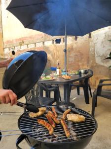 a person is cooking sausages on a grill at Casa Bella - Borne arcade, Baby-Foot, Extérieur in Thiers