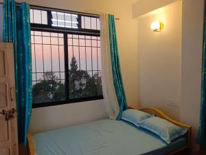 a bed in a room with a window at Green heaven homestay in Kalimpong