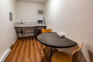 a small room with a table and a kitchen at Coastline Motel Kamloops in Kamloops