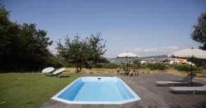 a swimming pool in a yard with chairs and umbrellas at CASA GRANDE DE JUNCAIS - SERRA DA ESTRELA in Fornos de Algodres
