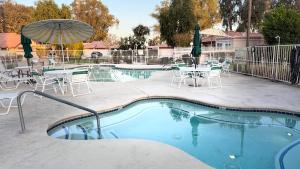 a pool with tables and chairs and an umbrella at Perfect Coachella Getaway! in Indio