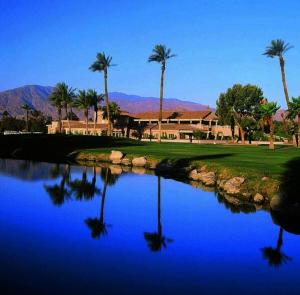 a golf course with palm trees and a pool of water at Perfect Coachella Getaway! in Indio