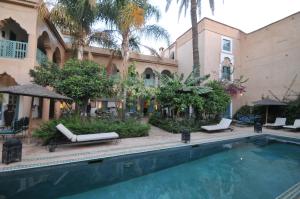 a swimming pool in front of a building with palm trees at Palais Oumensour in Taroudant