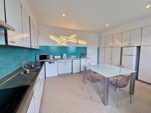 a kitchen with white cabinets and a table and chairs at Evian villa with Lake Geneva views in 1960 mid-century modern style in Neuvecelle