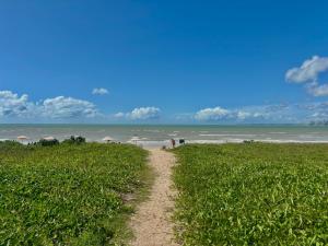 a dirt road leading to a beach with people on it at Viva o Paraíso – Condomínio Exclusivo Beira-Mar e Lazer Completo in Ilha da Restinga +20 photos