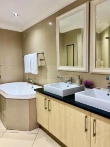 a bathroom with two sinks and a tub at Ocean & Canal Views - The Sails Apartment in Durban