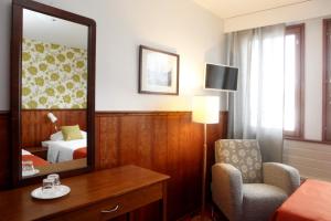 um quarto de hotel com um espelho e uma cadeira e uma cama em Hotelli Pogostan Hovi em Ilomantsi