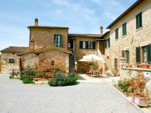 a large brick building with a patio and an umbrella at Cottage in Asciano with Pool and Terrace in Asciano