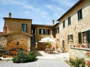 - un bâtiment en briques avec une terrasse dotée d'un parasol dans l'établissement Farmhouse in Tuscany with Pool & Scenic Views, à Asciano