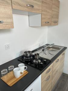 卡姆尼克Apartments Linden Tree的厨房配有炉灶和2个杯子(在切盘上)