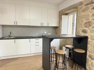 a kitchen with white cabinets and bar stools at PADRÓN PLAZA Lofts, Centro in Padrón