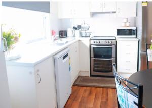 a kitchen with white cabinets and a stove top oven at Little Luxe Retreat in Findon