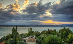 a sunset over the water with a house and trees at Hotel Astoria in Desenzano del Garda