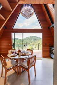 een eetkamer met een tafel en stoelen en een groot raam bij Kleines Paradies Chalés in Massaranduba