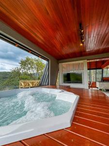 een groot bad in een kamer met een groot raam bij Kleines Paradies Chalés in Massaranduba